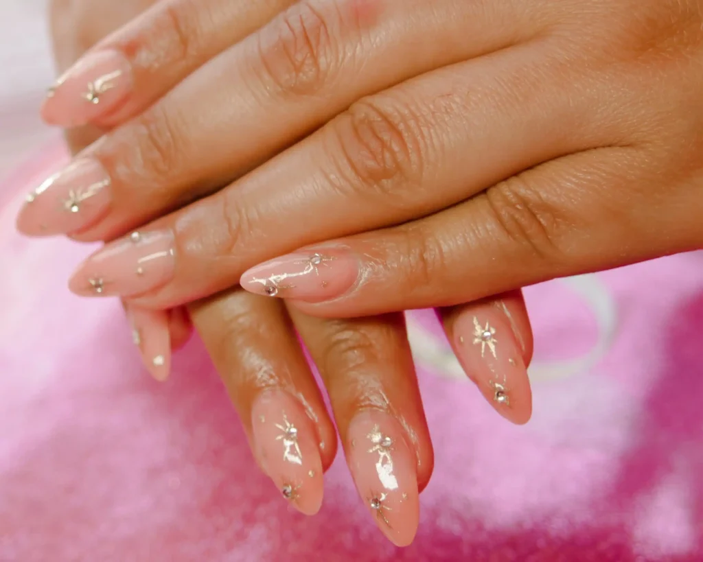 A close up of pink nails with star art and embellishments.